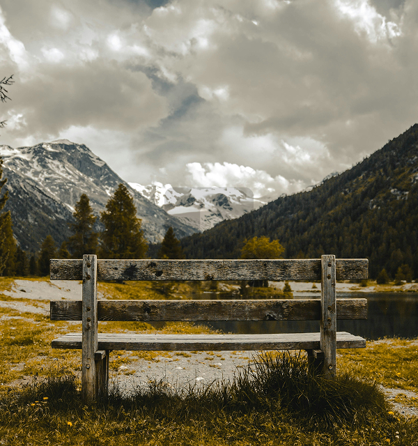 An empty wooden bench overlooking the mountains and glaciers of the Engadin valley